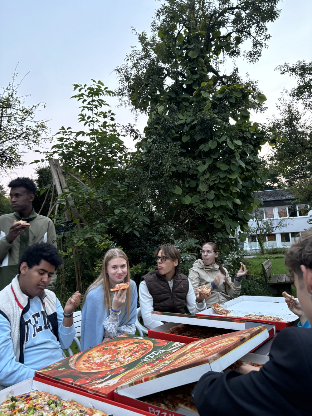 Die Teilnehmenden essen Pizza im Garten des Nordkollegs in Rendsburg.